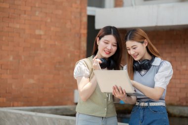 Asyalı genç kampüs öğrencisi birlikte ders çalışmayı ve kitap okumayı seviyor. Arkadaşlık ve eğitim kavramı. Kampüs ve üniversite.
