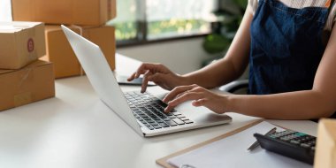 İnternetteki bir kadın, dizüstü bilgisayardaki müşteri adresini ve paket bilgilerini kontrol ediyor. Çevrimiçi alışveriş kavramı.