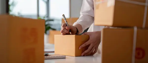 Woman entrepreneur prepare parcel box and check online order on laptop computer for commercial checking delivery. online marketing, packing box, SME seller. startup business concept.