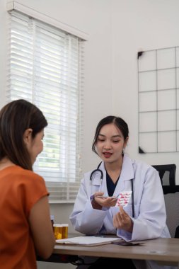 Doktor kadın, hasta doktor tarafından muayene edildikten sonra yaşlı kadın hastaya, eczacının sunduğu tedavi ve semptomatik ilaç konseptini tavsiye eder..