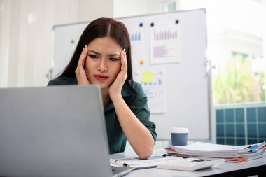 Ofiste baş ağrısı çekerken bilgisayarla çalışan stresli iş kadını.