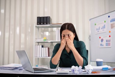 Ofiste baş ağrısı çekerken bilgisayarla çalışan stresli iş kadını.