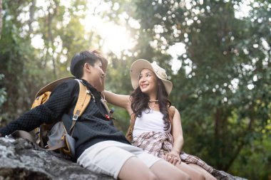 Sırt çantalı güzel lezbiyen kadın doğa yürüyüşü yaparken dinleniyor. Dağlarda romantik anları seven LGBT.