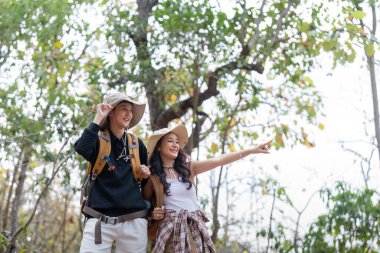 Sırtlarında sırt çantasıyla neşeli, romantik lezbiyen çift gezgin yazın dağlarda ormanda yürüyüşe çıkar..