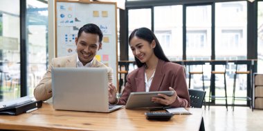 İş kadını ve erkek dijital tablet ve dizüstü bilgisayar kullanarak çalışıyor. Şirket toplantılarında finansal pazar verilerini tartışıyorlar..