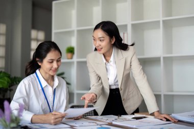 Modern bir ofiste projeyi tartışan iki genç iş kadını..