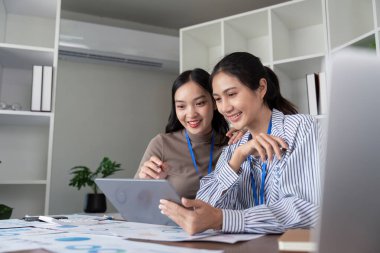 Modern bir ofiste bir proje üzerinde çalışan iki Asyalı kadın. Takım çalışması, işbirliği ve verimlilik kavramı.