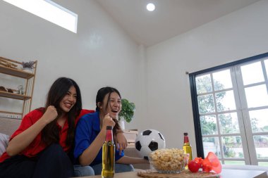 Asyalı lezbiyen çift, Avrupa futbol maçı için evde tezahürat yapıyor. Konsept neşe ve futbol.