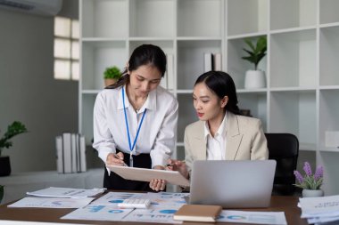 Ofisteki mali belgelerde iki iş kadını işbirliği yapıyor. Takım çalışması, veri analizi ve profesyonel işbirliği kavramı.