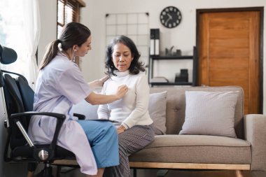 Doktor evdeki kanepede yaşlı kadını muayene ediyor. Sağlık ve fiziksel kontrol kavramı.