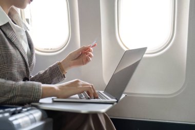 Uçuş sırasında bilgisayardan online alışveriş yapan iş kadını, uçuş verimliliği kavramı