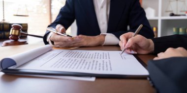 Profesyonel ofis ortamında iş sözleşmesi imzalayan bir avukat ve müvekkil, yasal hizmetleri, şirket anlaşmalarını ve iş anlaşmalarını sembolize eder..