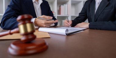 Profesyonel bir avukat ve müvekkil bir ofis ortamında iş sözleşmesi imzalıyor. Yasal anlaşma, iş anlaşması ve şirket hukukunu sembolize ediyor..