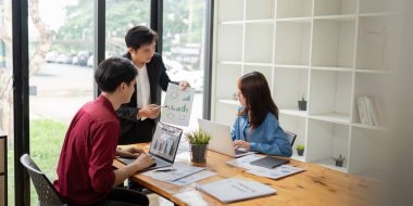 İş dünyası verileri analiz ediyor ve modern bir ofiste çizelgeler ve dizüstü bilgisayarlarla stratejileri tartışıyor, takım çalışması ve profesyonel işbirliği sergiliyor..