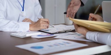 Bir toplantı sırasında analiz ve planlama üzerinde işbirliği yapan iş ekibi masasında çizelgeler ve belgelerle....