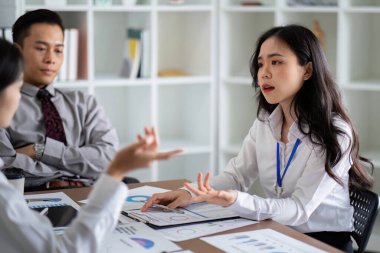 Profesyonel iş ekibi modern bir ofiste analiz ve planlama üzerine konuşuyor. Strateji ve verilere odaklanmış.