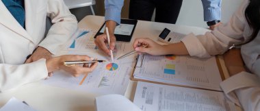 Bir iş ekibi finansal analiz ve strateji geliştirme konularını tartışır, modern ofis ortamında grafikleri ve grafikleri gözden geçirir..