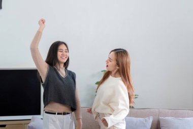 Mutlu lezbiyen çift dans ediyor ve modern bir oturma odasında birlikte vakit geçiriyorlar..