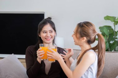 Mutlu lezbiyen çift birlikte portakal suyu içiyor, rahat ve modern bir ev ortamında sağlık ve refahı teşvik ediyorlar..