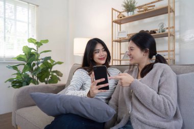 Sevgi dolu bir lezbiyen çift evde rahatlar, rahat ve modern bir oturma odasında bir anlık neşe ve bağlantı paylaşırlar..