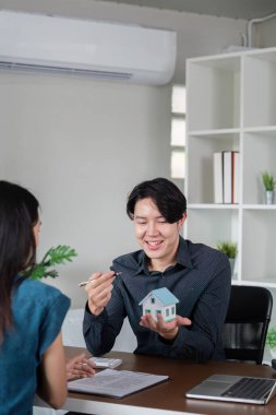 Emlakçı müşteriye modern ofis ortamında emlak alım-satımı için belge imzalamada yardımcı oluyor.