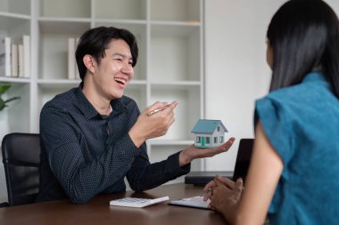 Emlakçı ve müşteri emlak satışını tartışıyor, belgeleri imzalıyor ve bir ev alıp satmak için anlaşma yapıyorlar..