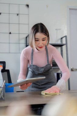 Profesyonel temizlikçi, çeşitli temizlik malzemeleri ve aletlerle modern bir evi temizliyor..