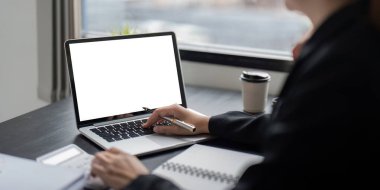 Boş ekranlı bir dizüstü bilgisayarın yer aldığı profesyonel bir iş alanı, modeller, sunumlar ve uzak çalışma ayarları için ideal.