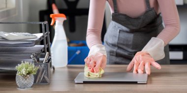 Modern bir ofis ortamında masa temizleme eldiveni takan hizmetçi..