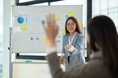 Modern ofis ortamında bir meslektaşına veri ve çizelge sunan profesyonel bir iş kadını..