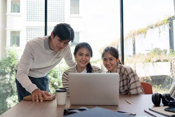 stock image Three students working together on a laptop in a bright, modern study room, showcasing teamwork and collaboration.