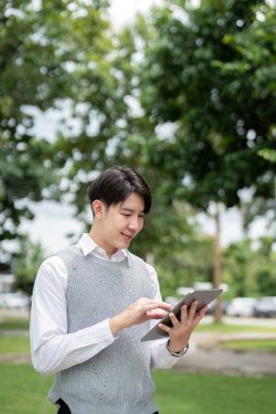 Açık hava tableti kullanan genç bir profesyonel, modern iş ve teknolojiyi doğal ortamında temsil ediyor..