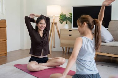 Sıcak bir oturma odasında yoga seansından zevk alan iki kadın, sağlık, sağlık ve pozitif bir yaşam tarzını destekliyor..