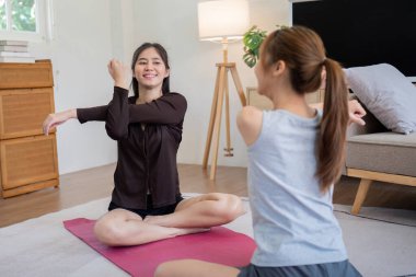 Evde yoga seansından zevk alan iki kadın sıcak ve destekleyici bir atmosfer yaratıyor..