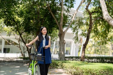 Bir iş kadını elektrikli bisikletle modern bir şehir ortamında çevre dostu ulaşım ve enerji korumasını savunuyor..