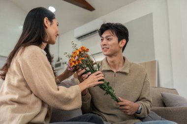 Sevgi dolu bir çift, samimi, modern bir ev ortamında çiçeklerini değiş tokuş ederken romantik ve sevgi dolu bir anı paylaşır..