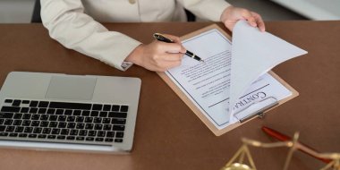 A professional lawyer in a beige suit reviews a contract at a desk with a laptop and legal documents, symbolizing legal expertise and professionalism. clipart