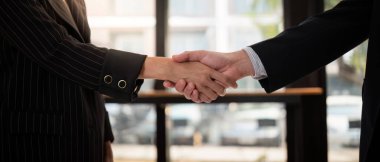 Resmi giyinmiş iki iş adamı arasındaki profesyonel tokalaşma, anlaşma, ortaklık ve başarılı işbirliğini sembolize ediyor..