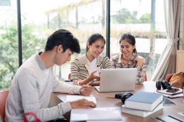Bir grup öğrenci, araştırma ve işbirliği için dizüstü bilgisayarlar ve kitaplar kullanarak, parlak ve modern bir çalışma alanında bir proje üzerinde birlikte çalışıyorlar..