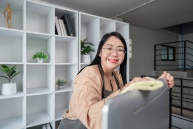 Modern bir evde bezle temizlik yapan neşeli bir hizmetçi. Profesyonel hizmetçi hizmetleri ve ev temizliği sunar.