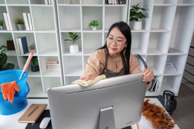 Kendini işine adamış bir temizlikçi titizlikle bir ofis masasını bezle temizler, tertemiz ve düzenli bir çalışma alanı sağlar..