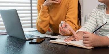 Evde bir proje üzerinde çalışan bir anne ve kız dizüstü bilgisayar ve defter kullanarak öğrenme ve bağlanmayı teşvik ediyor..