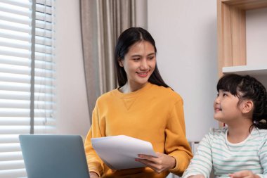 Bir anne ve kızı evlerinde keyifli bir anı paylaşıyor, bir dizüstü bilgisayarla çalışıyor ve belgeleri tutuyor, aile bağlarını ve birlikteliklerini gösteriyor..