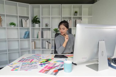 Modern bir ofis masasında renk paletleri ve tasarım kavramları üzerinde çalışan bir grafik tasarımcısı..