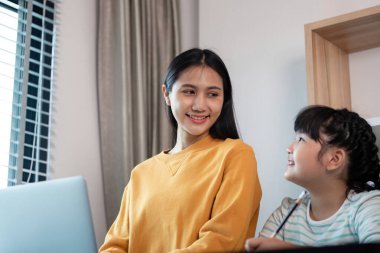 Bir anne ve kızı arasındaki samimi bir an, gülümsemelerini paylaşmak ve sıcak bir yuva ortamında birbirlerine eşlik etmek..