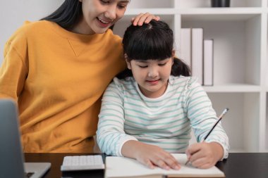 Sevgi dolu bir anne, kızına ev ödevlerinde yardım eder. Modern bir ev ortamında sıcak ve destekleyici bir ortam yaratır..