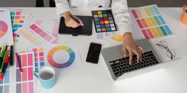 Modern ofis ortamında yaratıcı işler için renk paletleri, dijital tablet ve dizüstü bilgisayar kullanan grafik tasarımcısı.