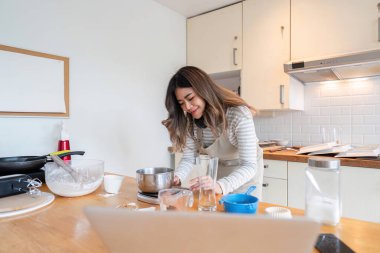 Neşeli ev fırıncısı modern mutfağında malzemeleri coşkuyla hazırlıyor. Ev yapımı aşçılık tutkusunun özünü yakalar..