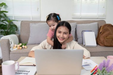 Sevgi dolu bir anne ve çocuğu evlerinde dizüstü bilgisayarla uğraşırken sıcak bir anı paylaşıyorlar, aile ile dijital öğrenmeyi birleştiriyorlar..