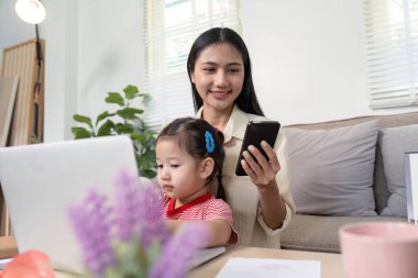 Ana teknolojiyi dengelemek ve evde ebeveynlik yaparken akıllı telefonu ve dizüstü bilgisayarı ile kızının yanında etkileşime girmek..